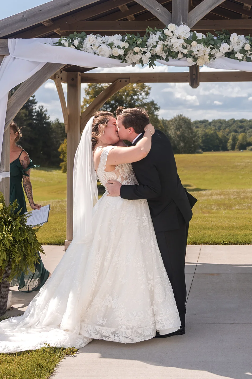 bride and groom first kiss under ceremony arbor