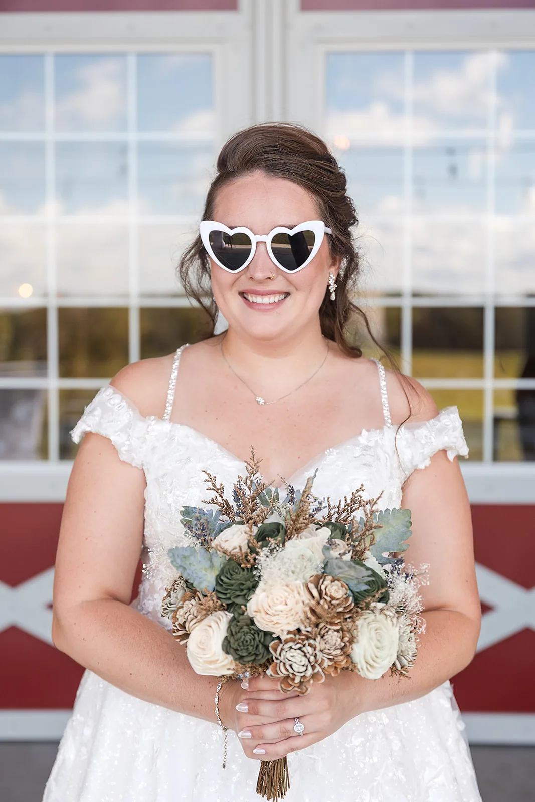 bride in heart-shaped sunglasses holding bouquet, barn window backdrop
