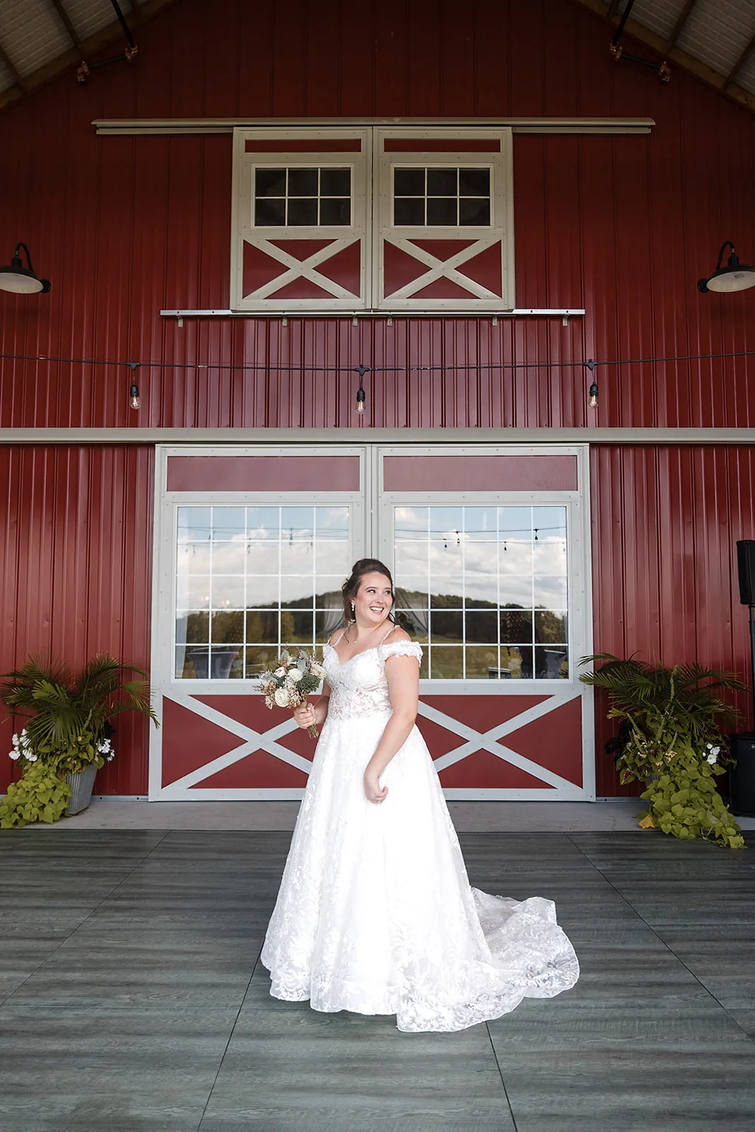 bride standing at red barn doorway, full dress shot