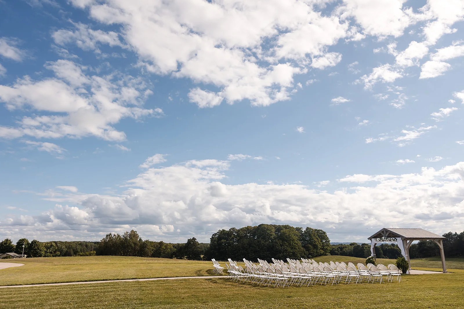 wide landscape of ceremony field with white chairs set up
