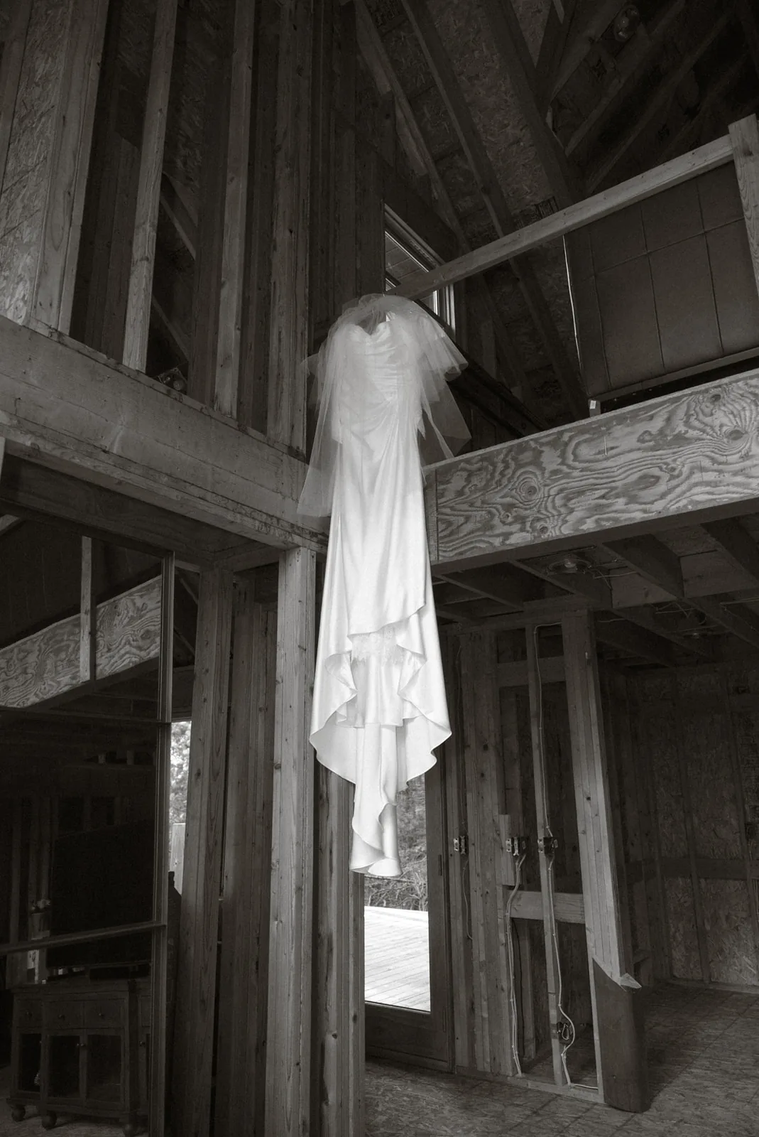 bw detail of wedding dress hanging on rustic wood beam