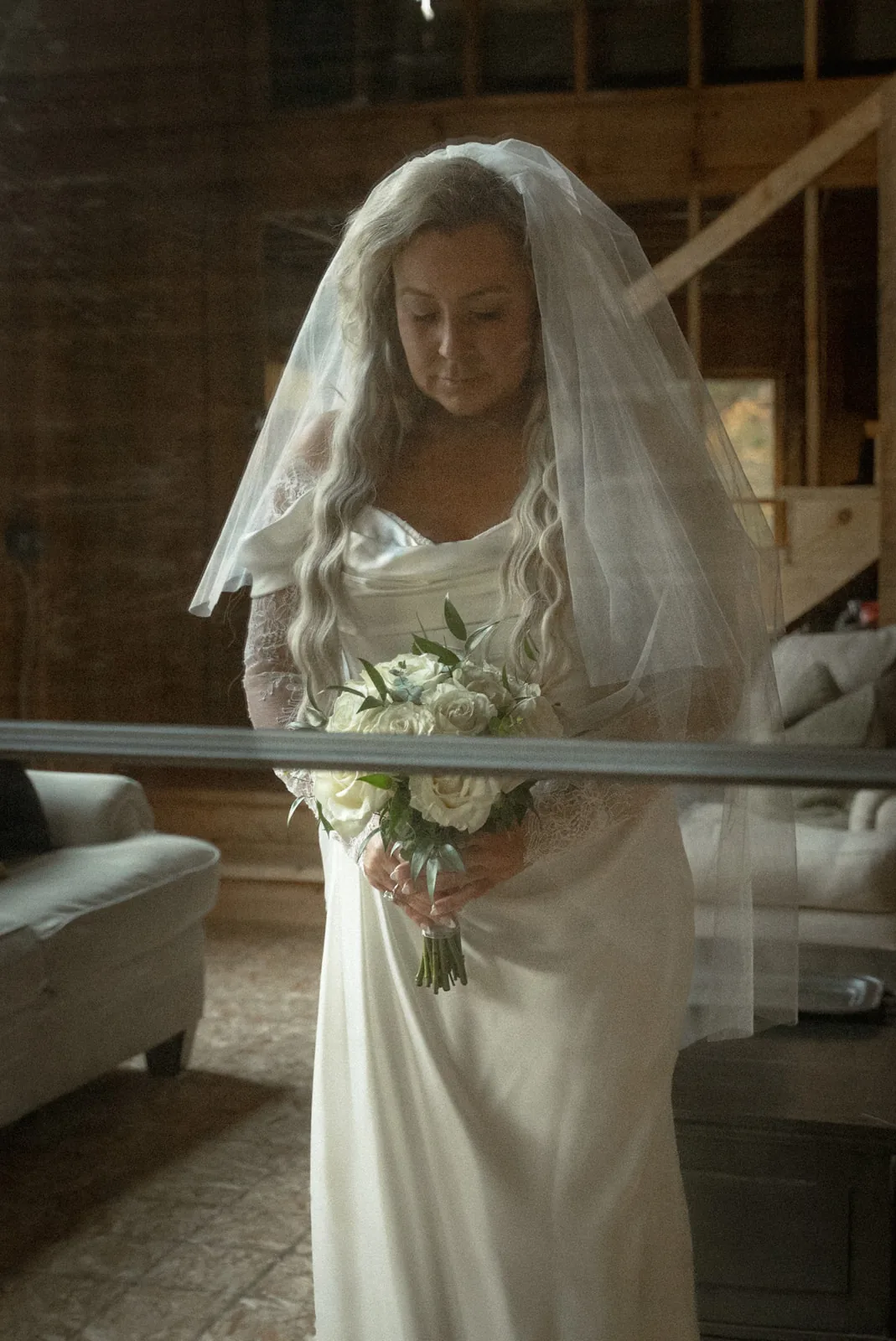bride holding bouquet, looking down pensively indoors