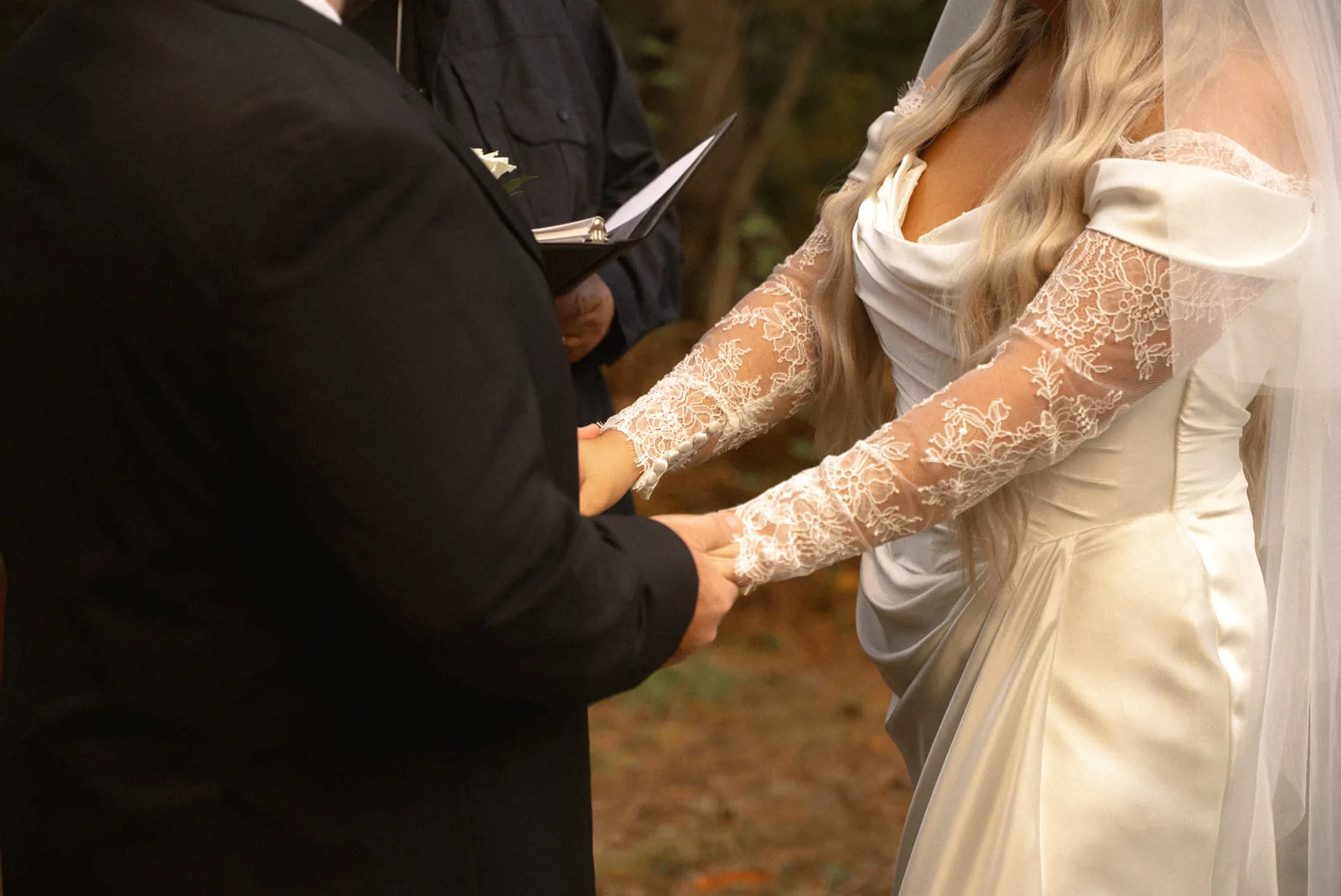 close-up of officiant placing ring on bride hand during ceremony