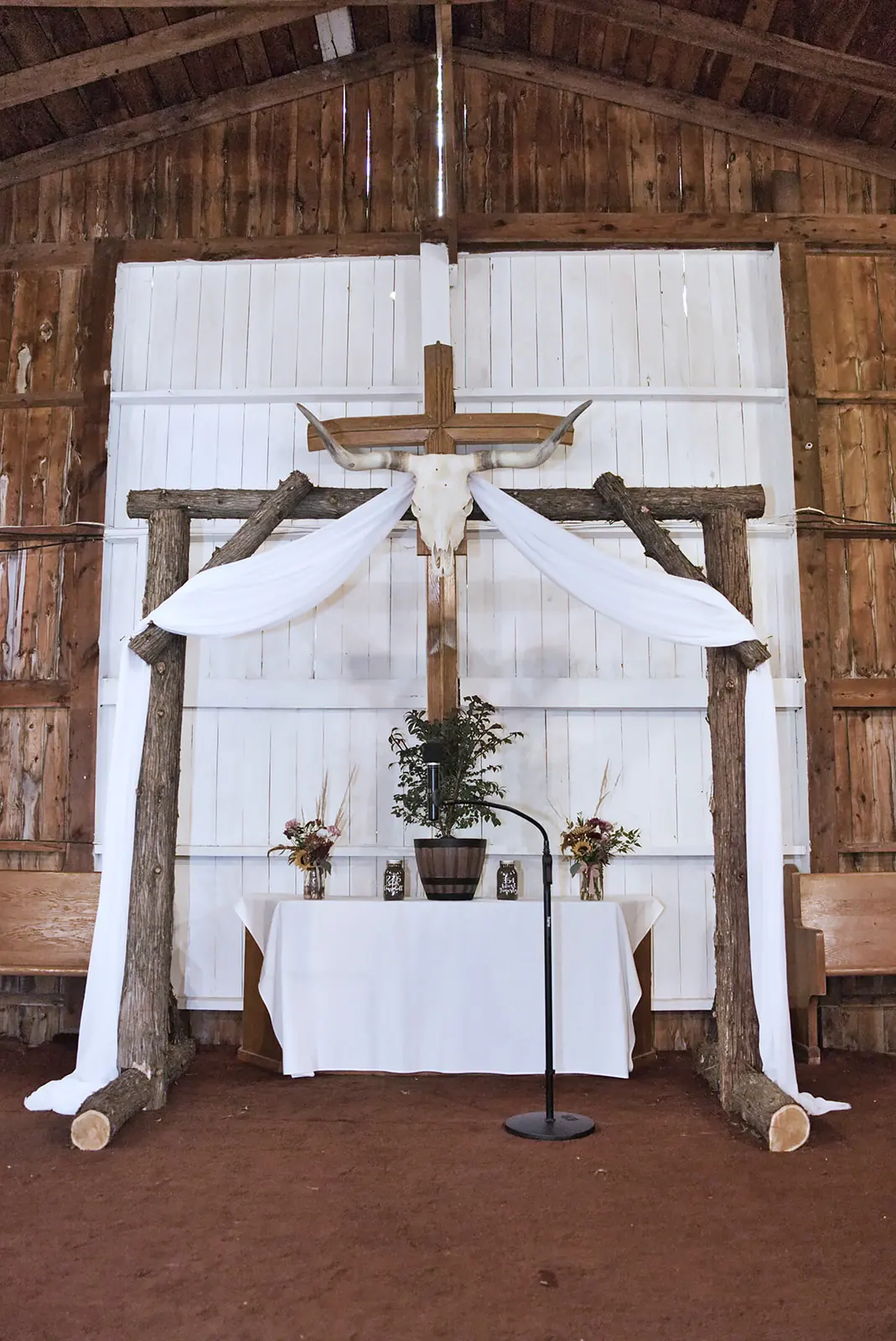 Barn ceremony altar white drape arch — Chelsea & Jake's wedding at Ogemaw County Fairgrounds, West Branch, MI