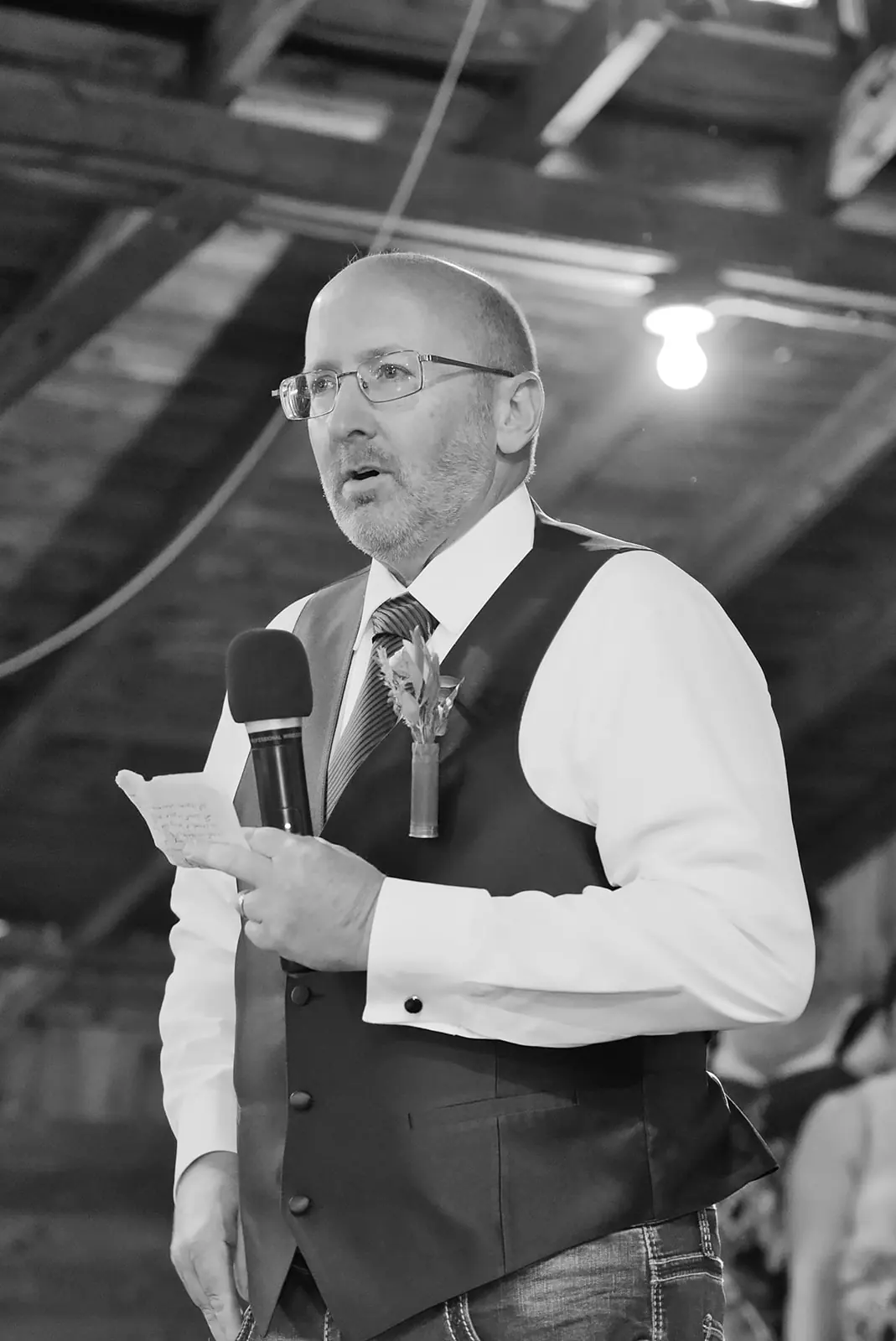 Black white speaker vest holding microphone — Chelsea & Jake's wedding at Ogemaw County Fairgrounds, West Branch, MI
