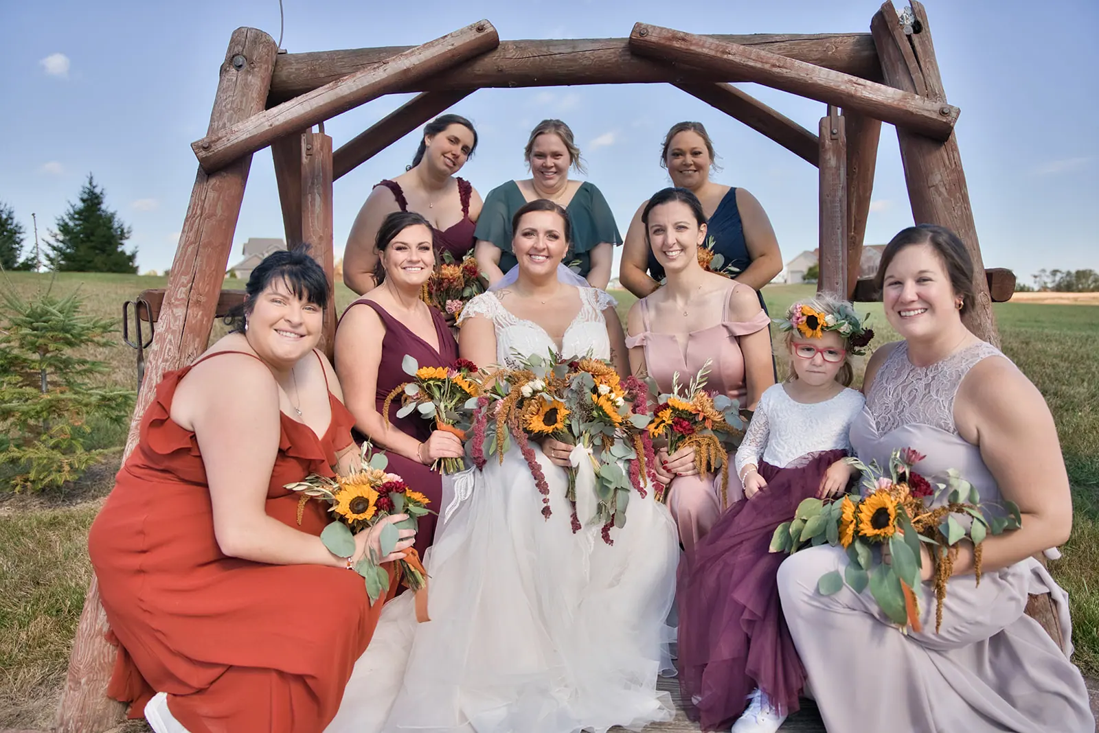 Bridesmaids red burgundy rustic log arbor — Chelsea & Jake's wedding at Ogemaw County Fairgrounds, West Branch, MI