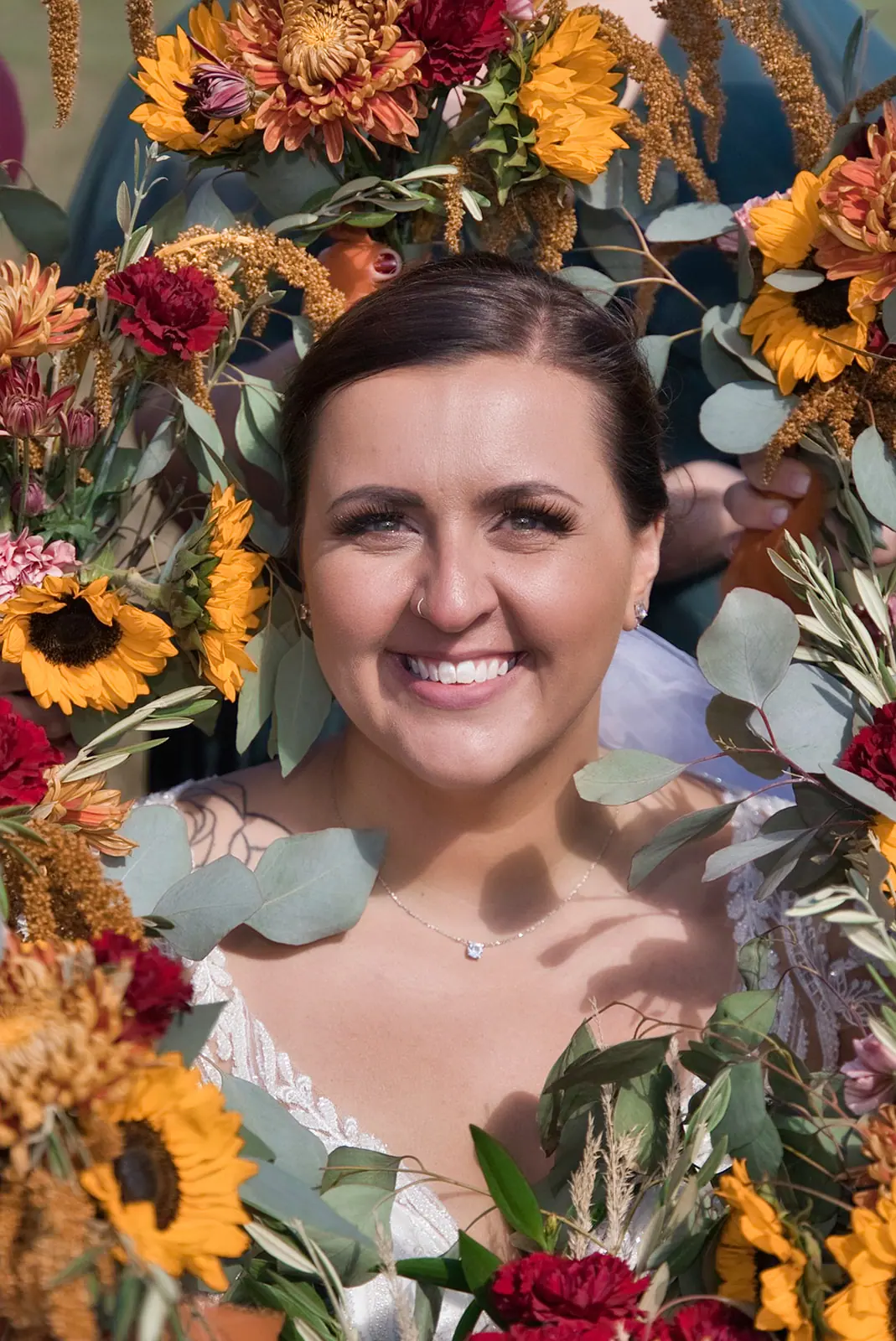 Close bride framed sunflowers eucalyptus smiling — Chelsea & Jake's wedding at Ogemaw County Fairgrounds, West Branch, MI