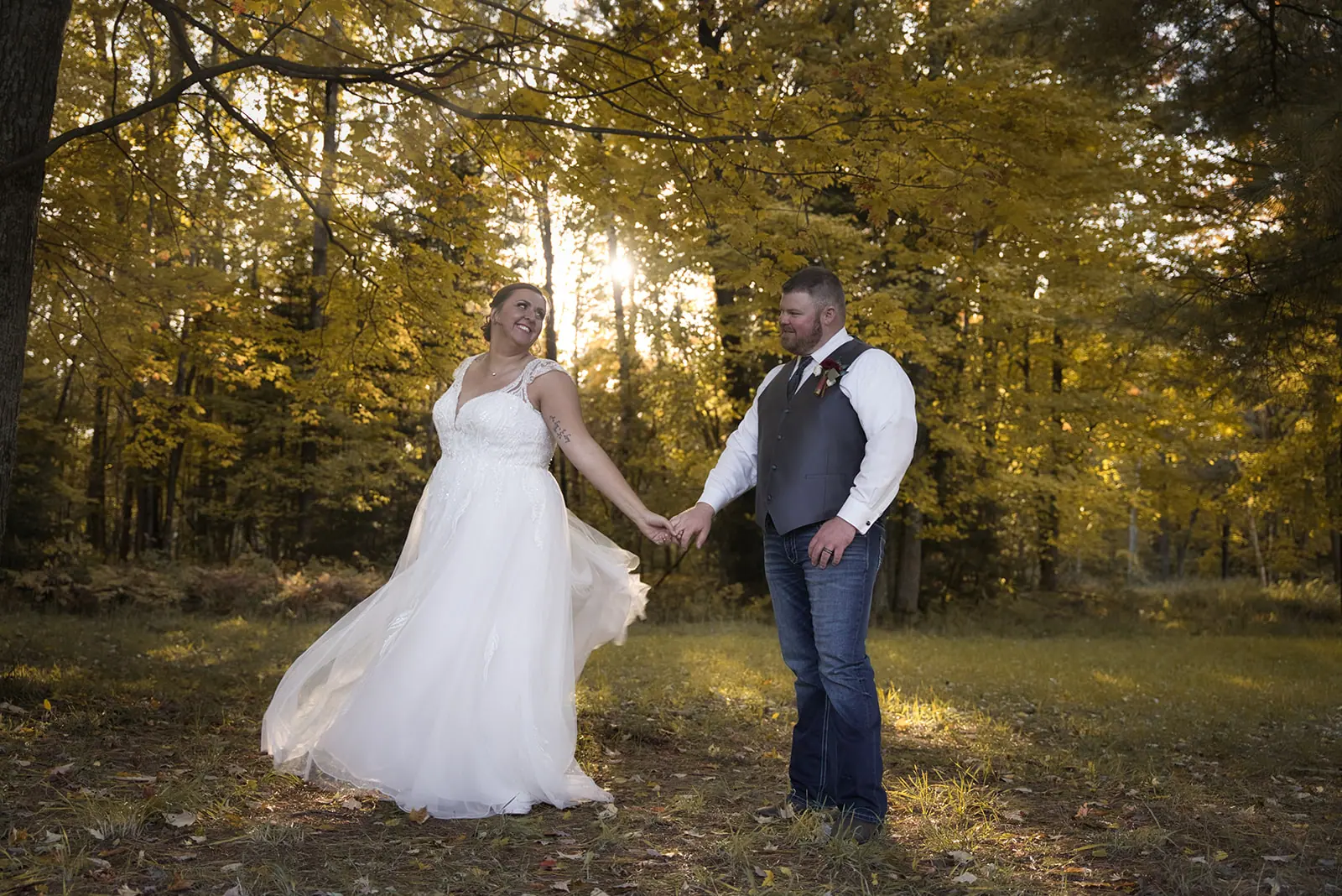 Couple holding hands walking through woods — Chelsea & Jake's wedding at Ogemaw County Fairgrounds, West Branch, MI