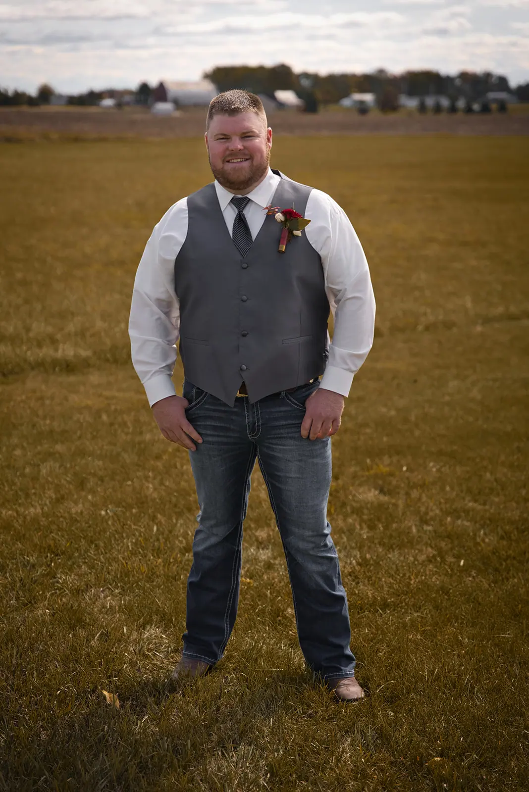 Groom standing alone autumn field vest — Chelsea & Jake's wedding at Ogemaw County Fairgrounds, West Branch, MI