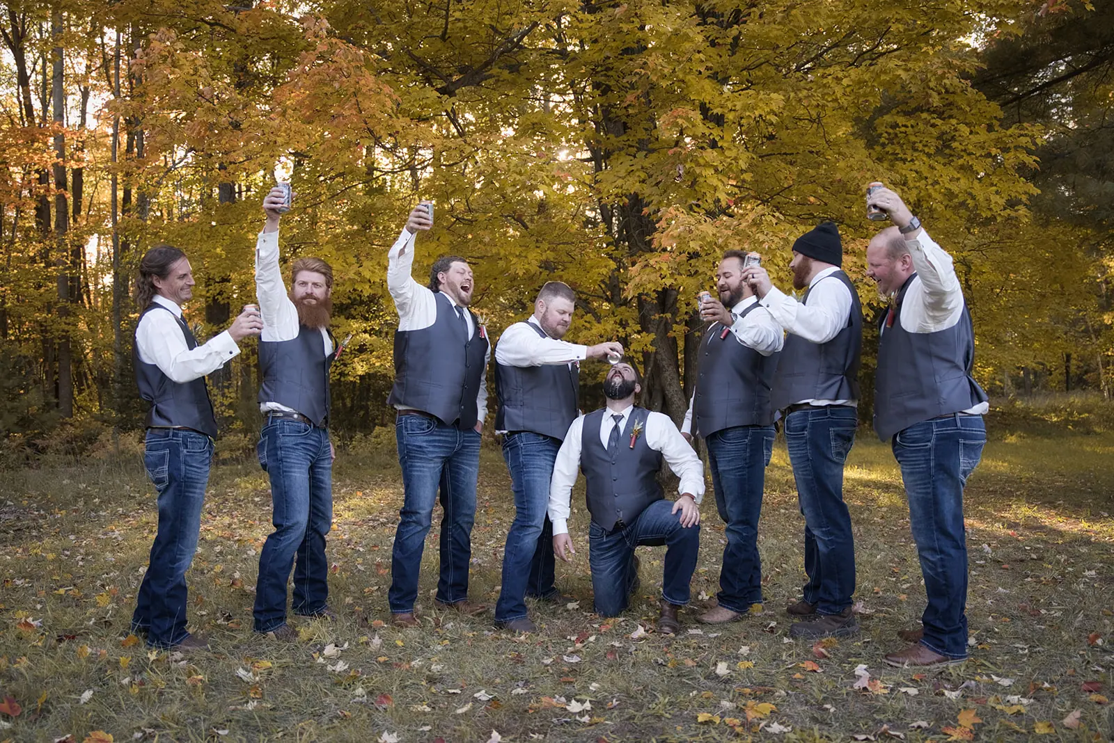 Groomsmen grass field toasting drinks laughing — Chelsea & Jake's wedding at Ogemaw County Fairgrounds, West Branch, MI