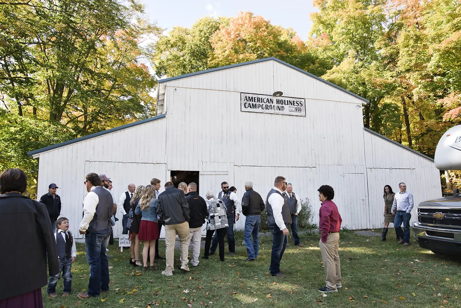 Guests gathered outside white barn fall — Chelsea & Jake's wedding at Ogemaw County Fairgrounds, West Branch, MI