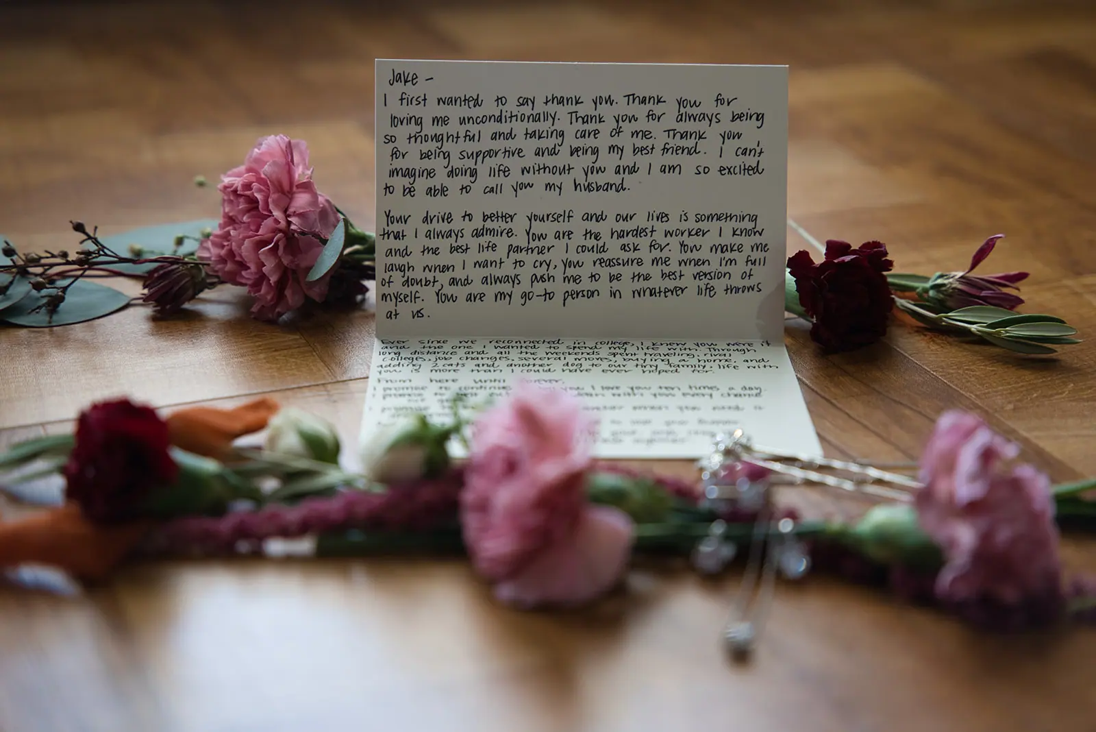 Handwritten vows letter table between pink — Chelsea & Jake's wedding at Ogemaw County Fairgrounds, West Branch, MI