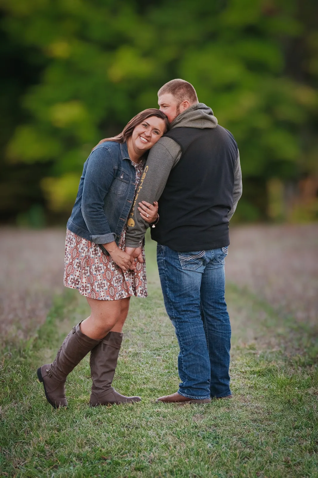 couple embracing in field, fall colors behind them