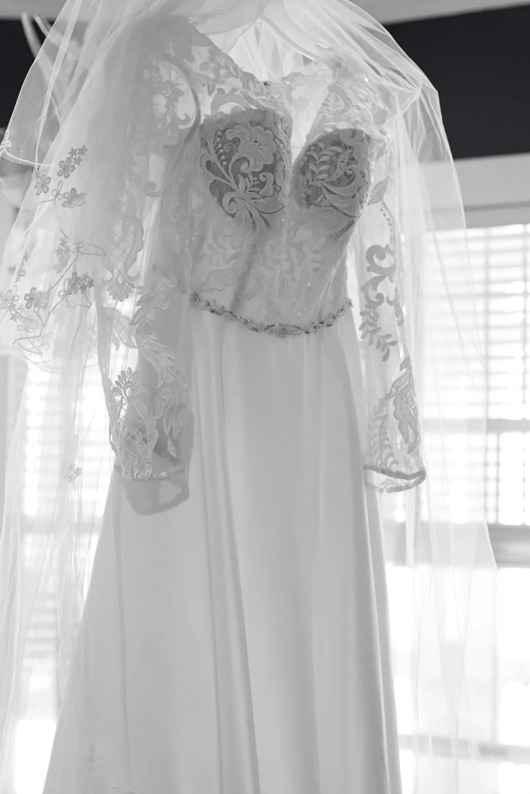 bw detail of wedding dress bodice hanging by window