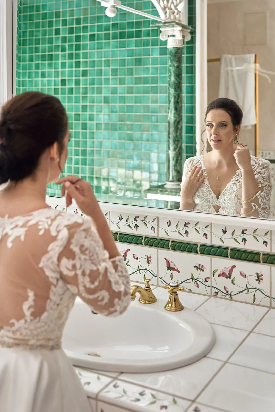 bride applying makeup in vintage green-tile bathroom mirror
