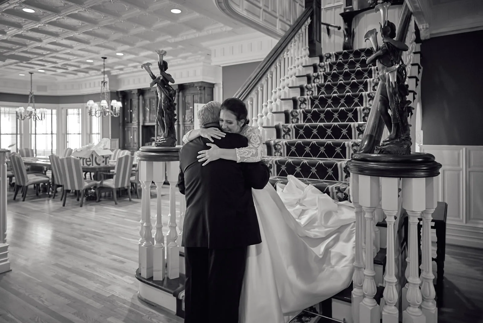 bw wide shot bride descending ornate staircase, groom waiting below