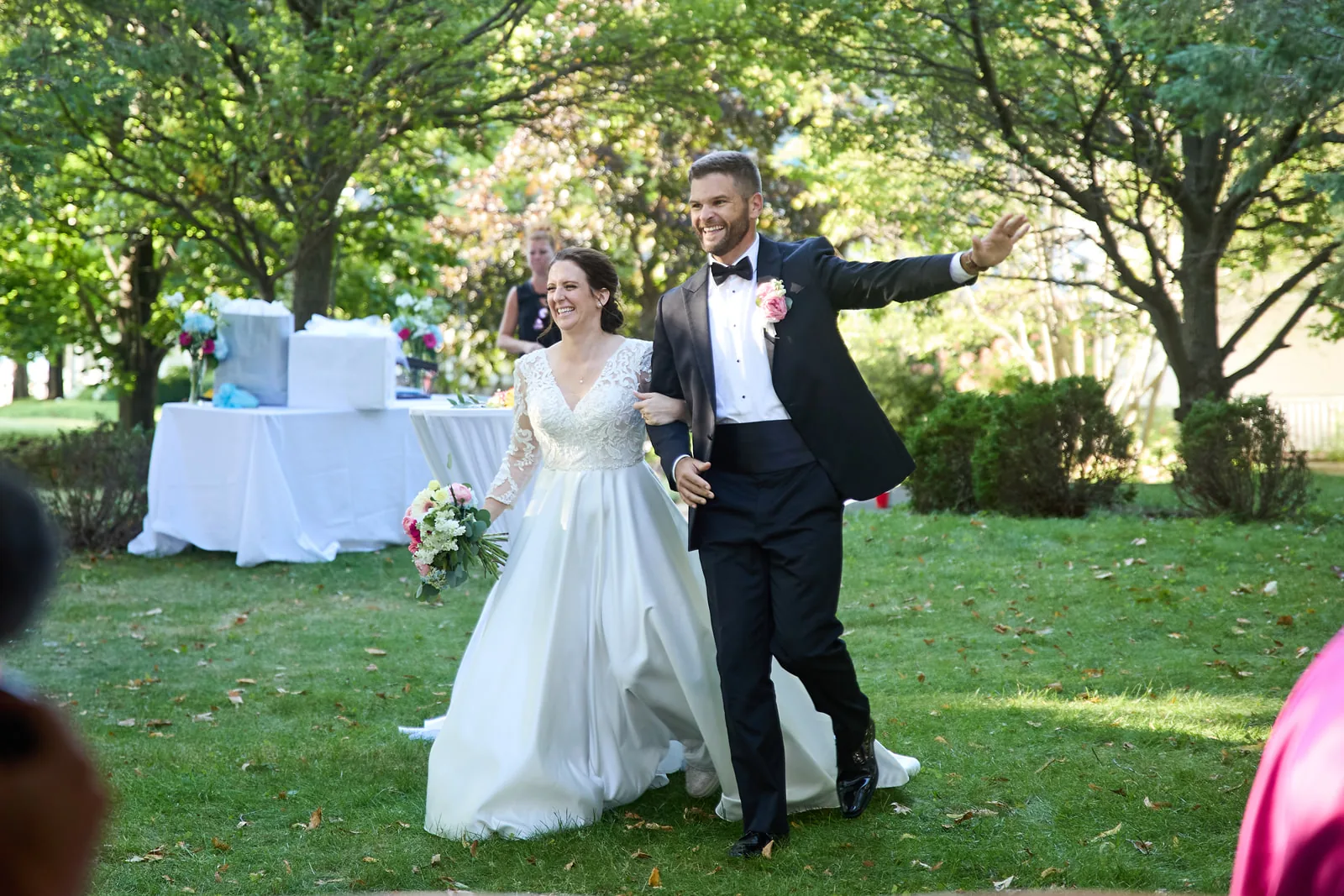 bride and groom running across lawn arms raised, exiting reception