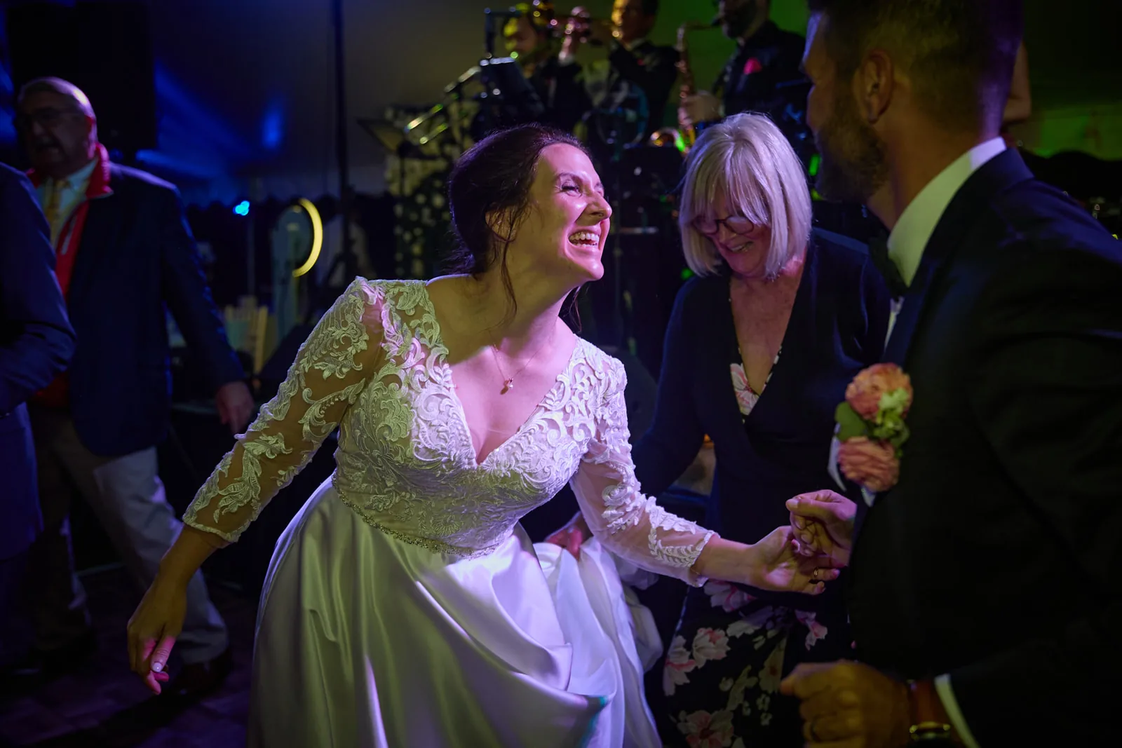 reception candid - bride dancing with guests, colorful lighting