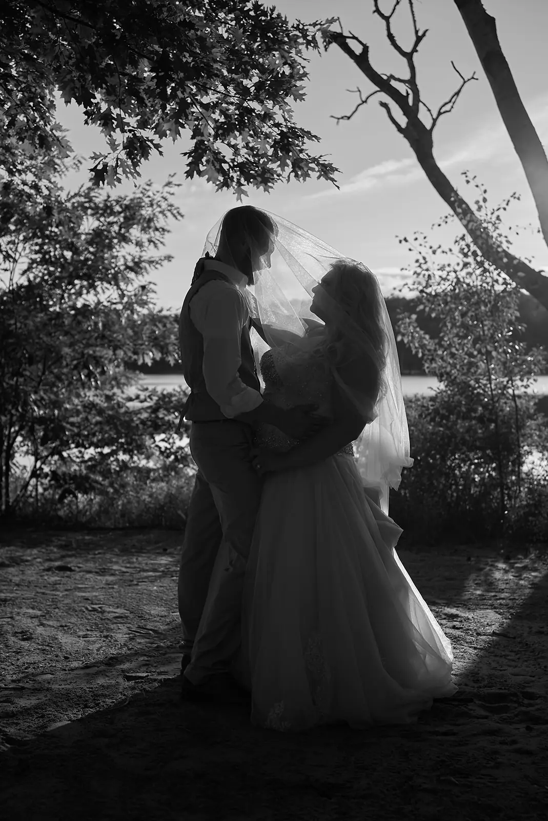 Black white couple embracing tree water — Erika & Corey's wedding at Sojourn Lakeside Resort, Gaylord, MI