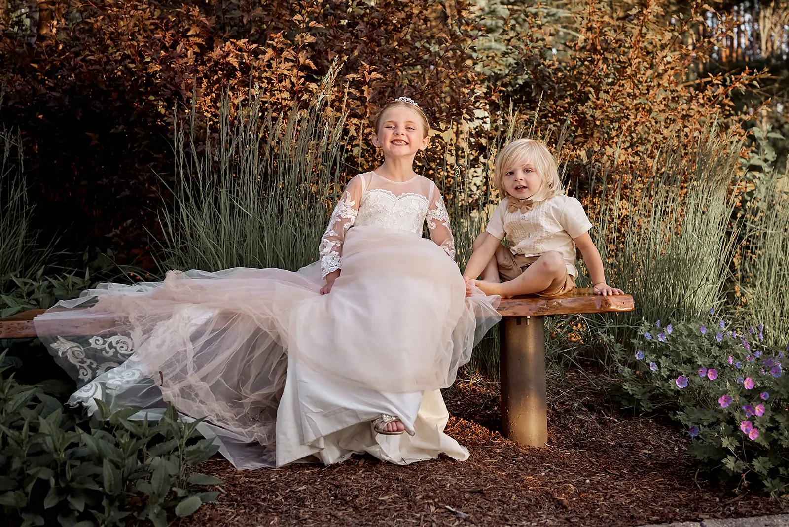 Bride flower girl seated log bench — Erika & Corey's wedding at Sojourn Lakeside Resort, Gaylord, MI
