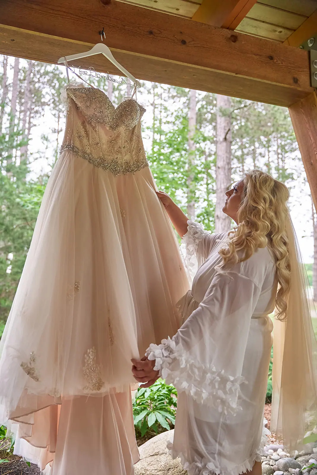 Bride holding gown hanging beam pavilion — Erika & Corey's wedding at Sojourn Lakeside Resort, Gaylord, MI