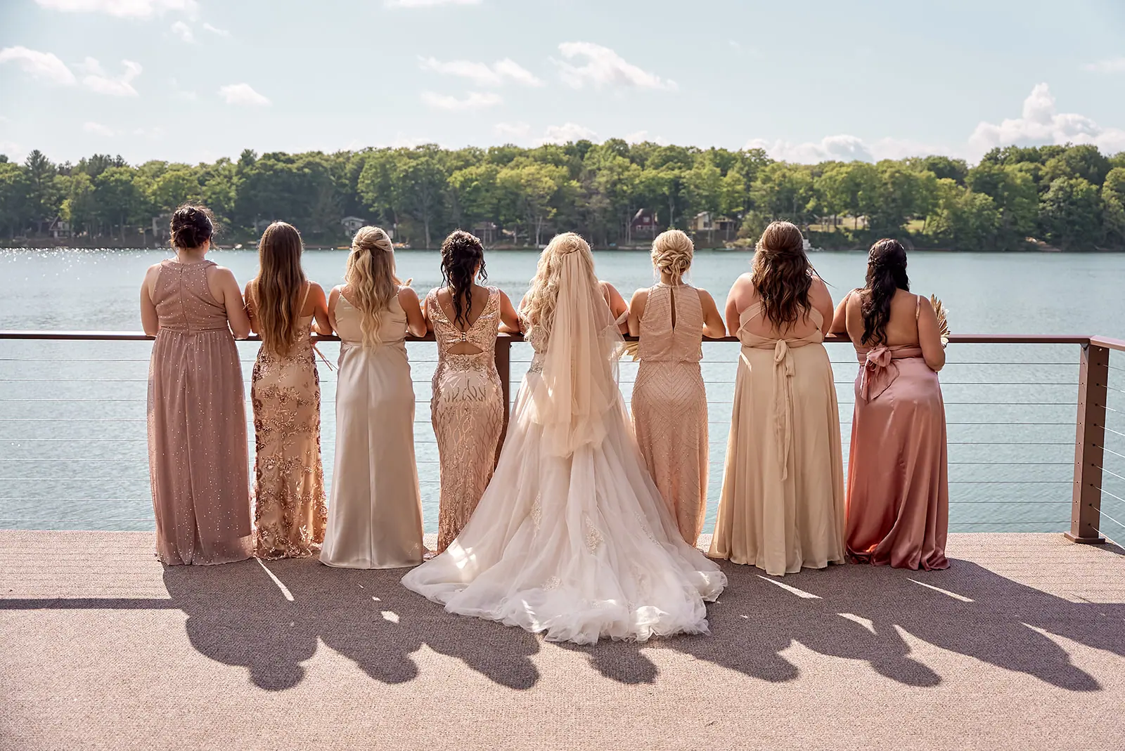 Bridesmaids bride lined deck backs camera — Erika & Corey's wedding at Sojourn Lakeside Resort, Gaylord, MI