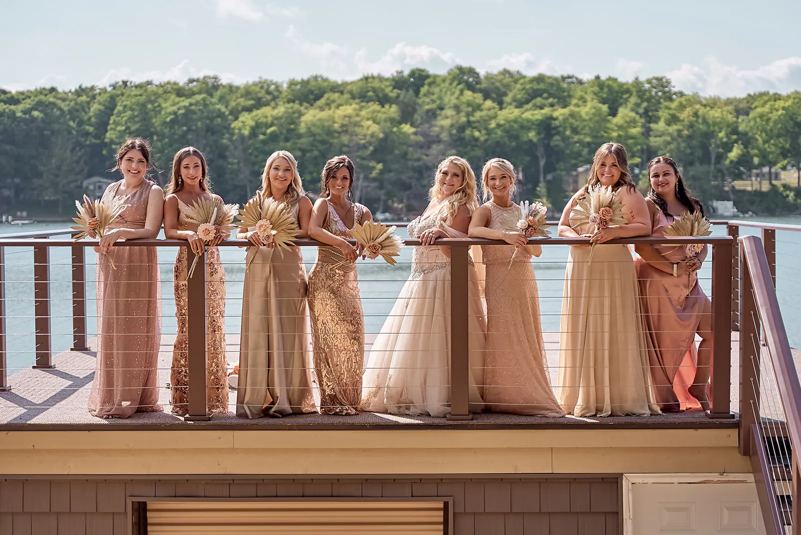 Bridesmaids leaning deck railing lake — Erika & Corey's wedding at Sojourn Lakeside Resort, Gaylord, MI