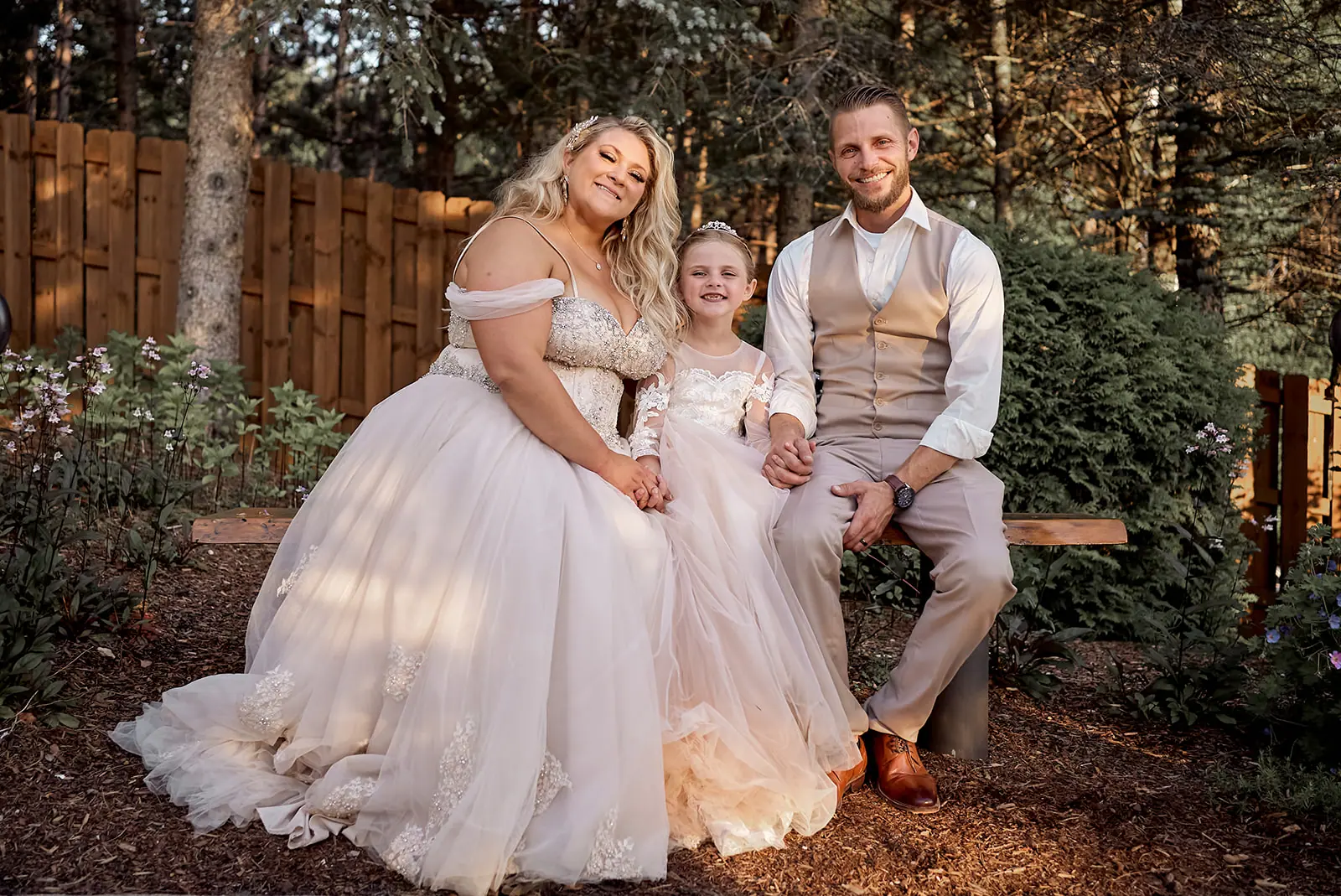 Couple seated garden bench child between — Erika & Corey's wedding at Sojourn Lakeside Resort, Gaylord, MI