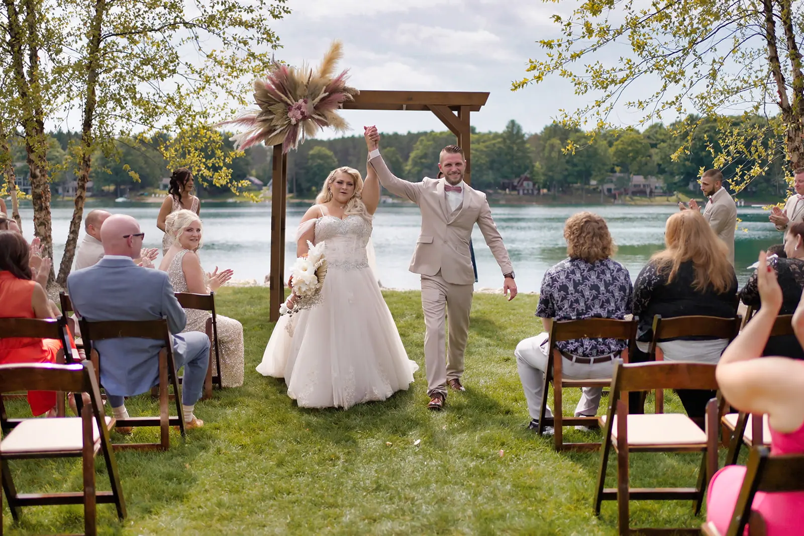 Couple walking back aisle arch guests — Erika & Corey's wedding at Sojourn Lakeside Resort, Gaylord, MI