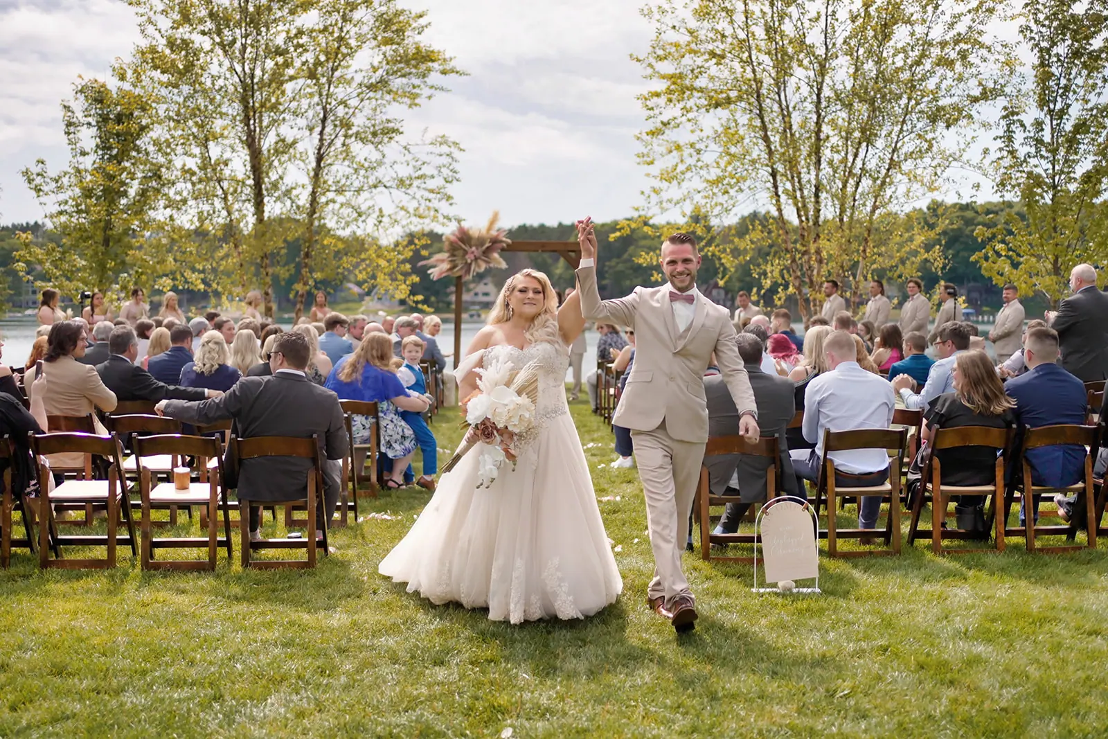 Couple walking back aisle arms raised — Erika & Corey's wedding at Sojourn Lakeside Resort, Gaylord, MI