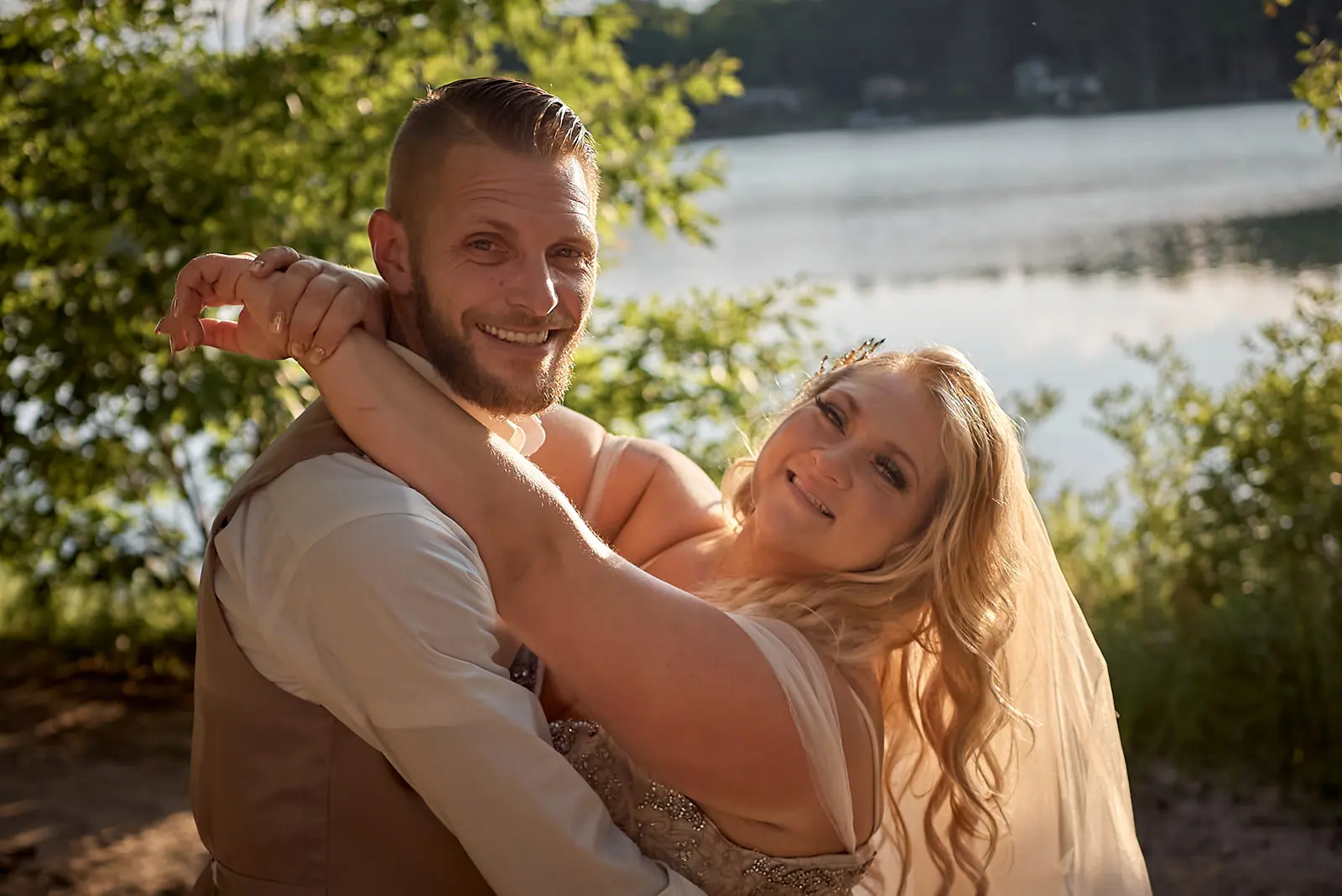 Groom smiling he hugs bride lake — Erika & Corey's wedding at Sojourn Lakeside Resort, Gaylord, MI