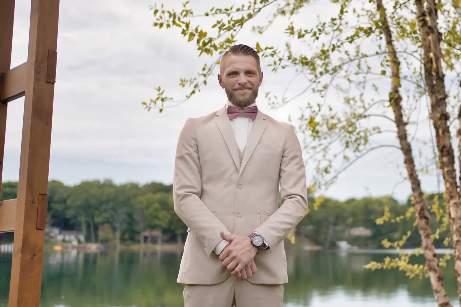 Groom tan suit pink tie standing — Erika & Corey's wedding at Sojourn Lakeside Resort, Gaylord, MI