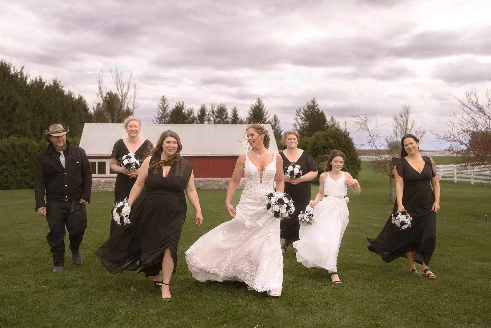 groomsmen group laughing and hugging bride candidly, overcast field