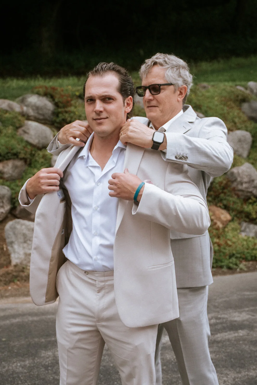 father helping groom with jacket, getting ready