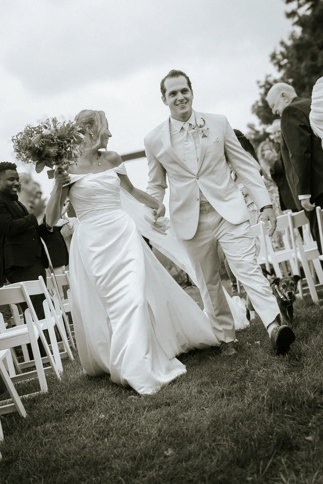 bw wide shot bride and groom running down aisle after ceremony, celebratory