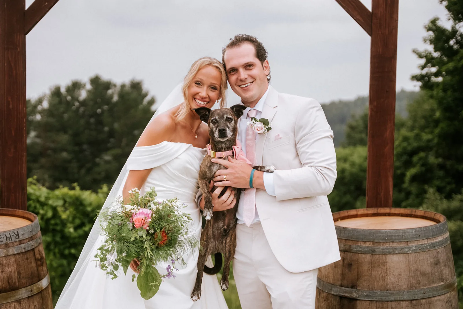 couple kneeling with dog Loui, bouquet, candid affectionate moment