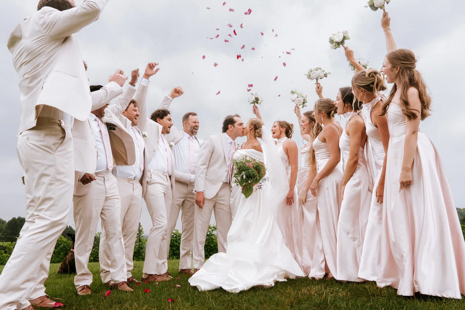 wedding party throwing flower petals into the air, overcast sky, celebratory