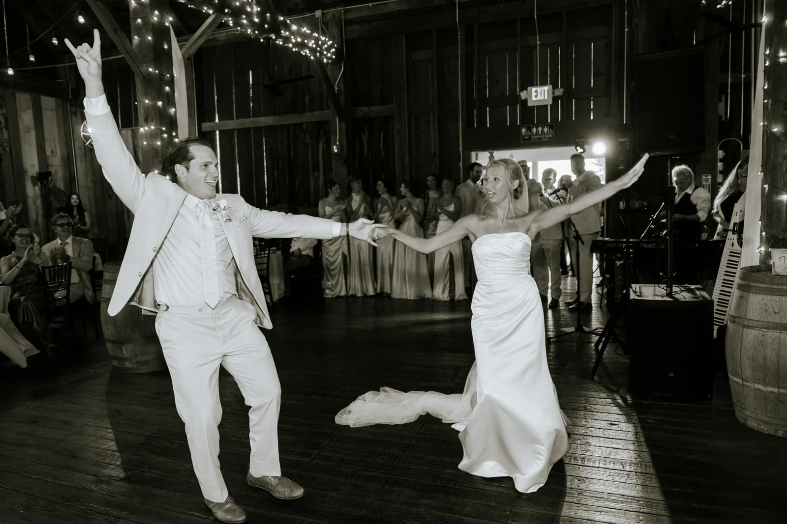sepia-tone first dance, groom and bride dancing exuberantly on barn stage, band visible