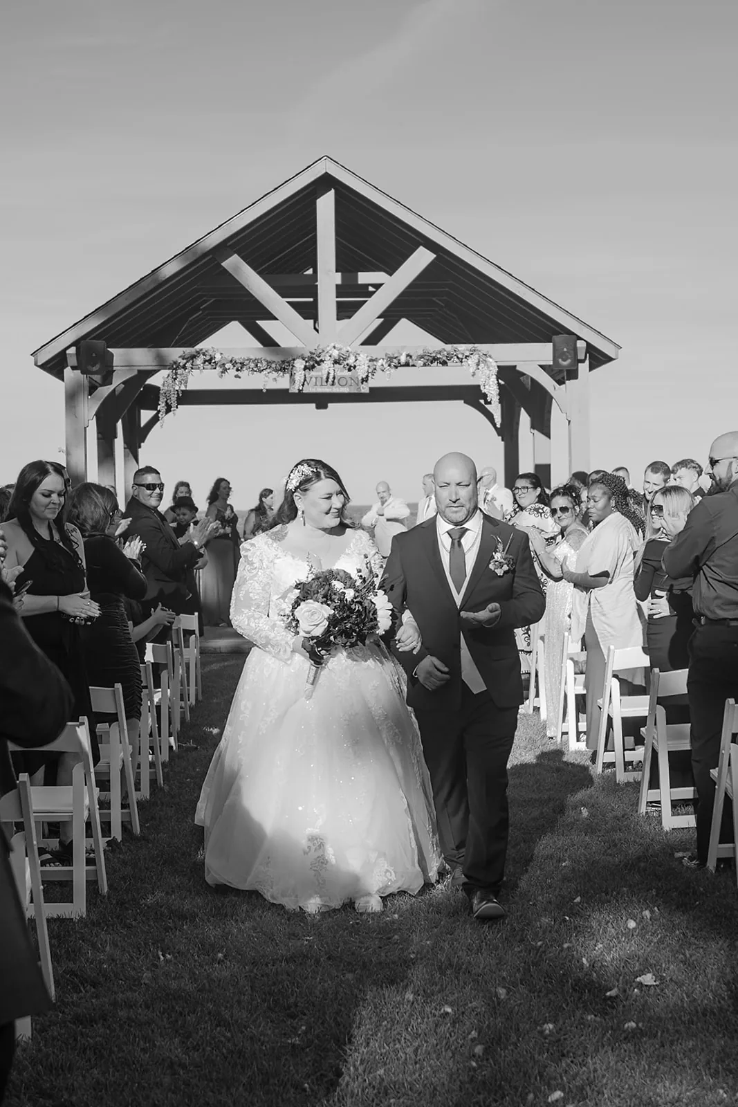 wide shot of wooden pavilion ceremony arbor, bridesmaids in sage, groomsmen in tan