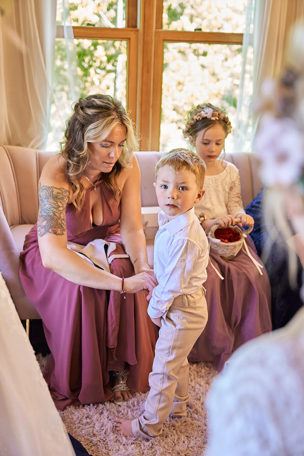 bride helping ring bearer boy with outfit, getting ready