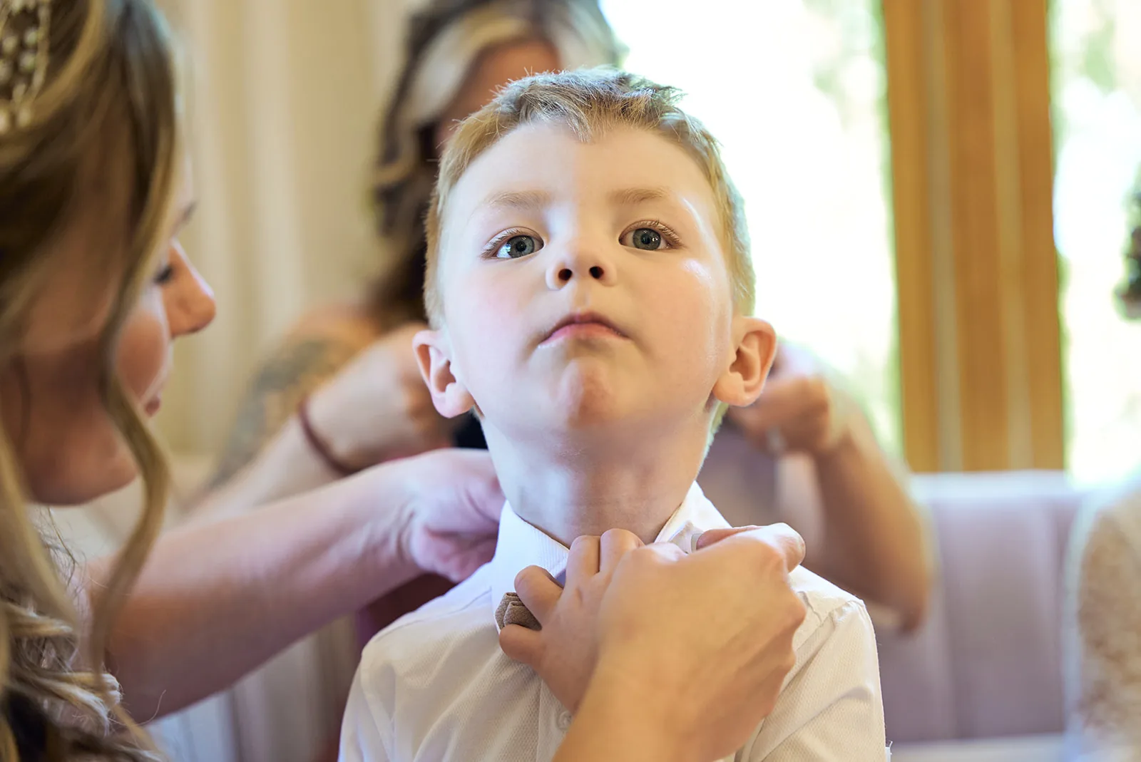 bride adjusting ring bearer bow tie, close-up candid