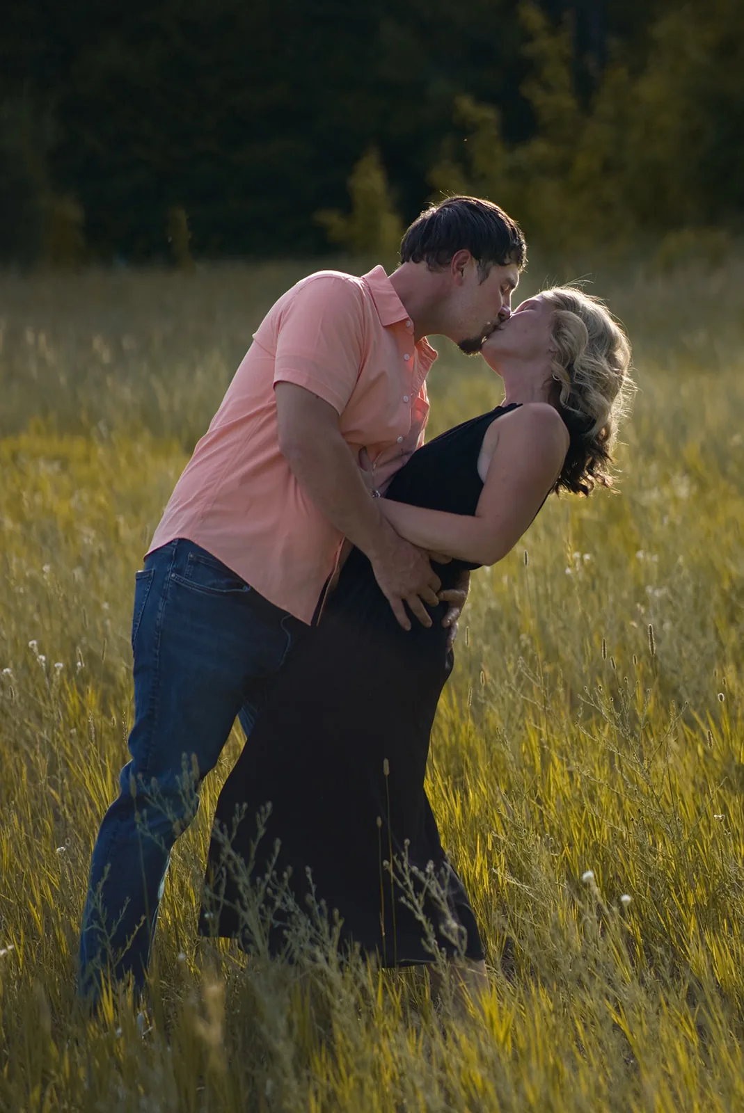 couple kissing in golden grass field at sunset
