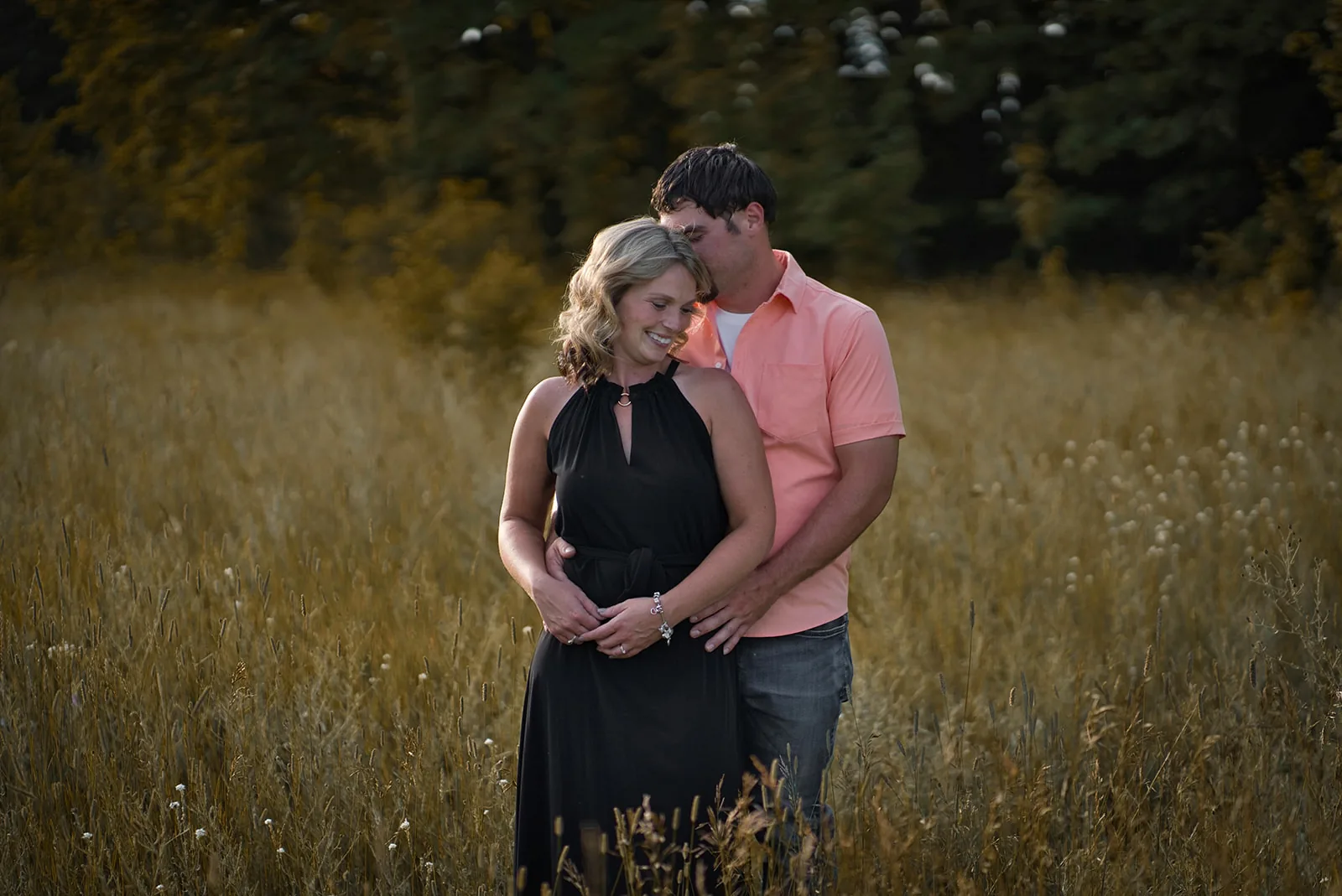 couple embracing in golden grass field, close portrait