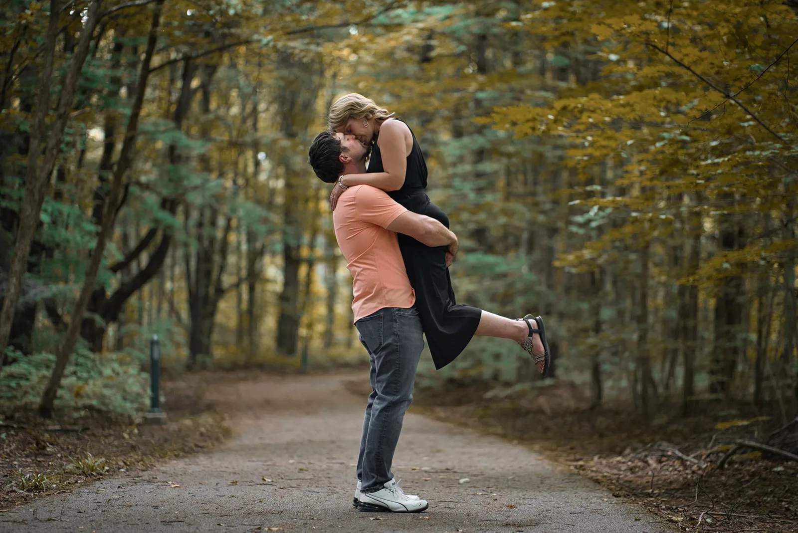 groom lifting bride in playful hug on forest path