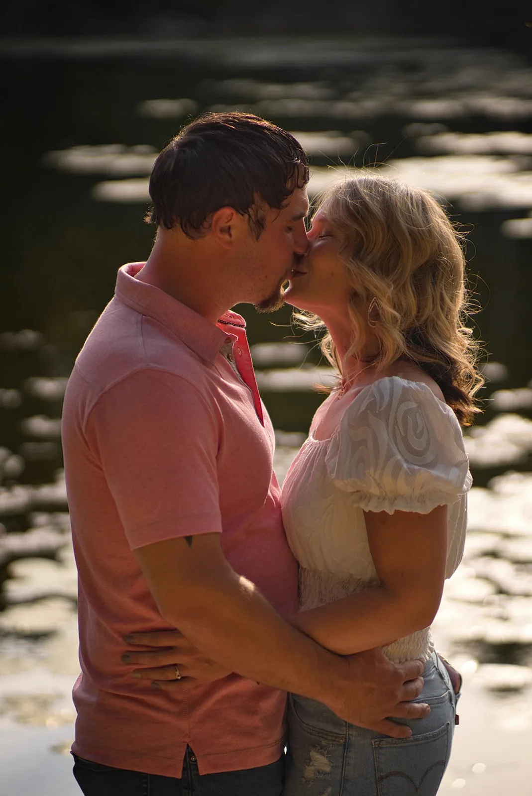 couple close-up kiss portrait by pond in forest, dusk