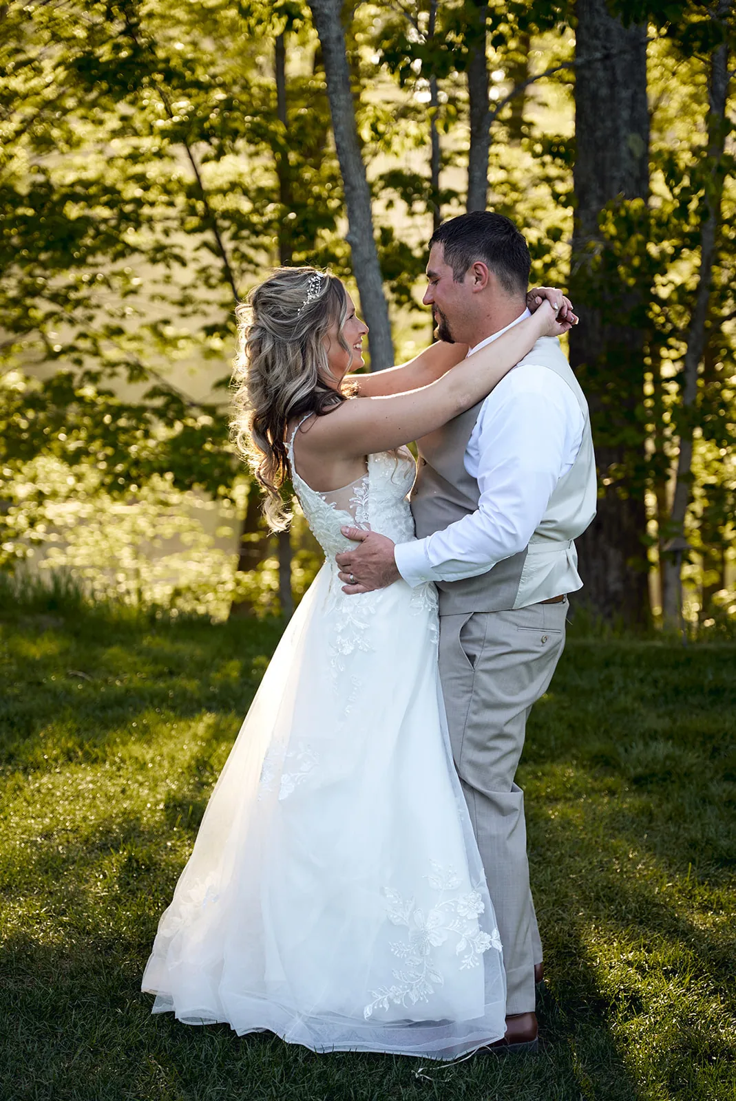 bride and groom dancing embrace on lawn, golden light