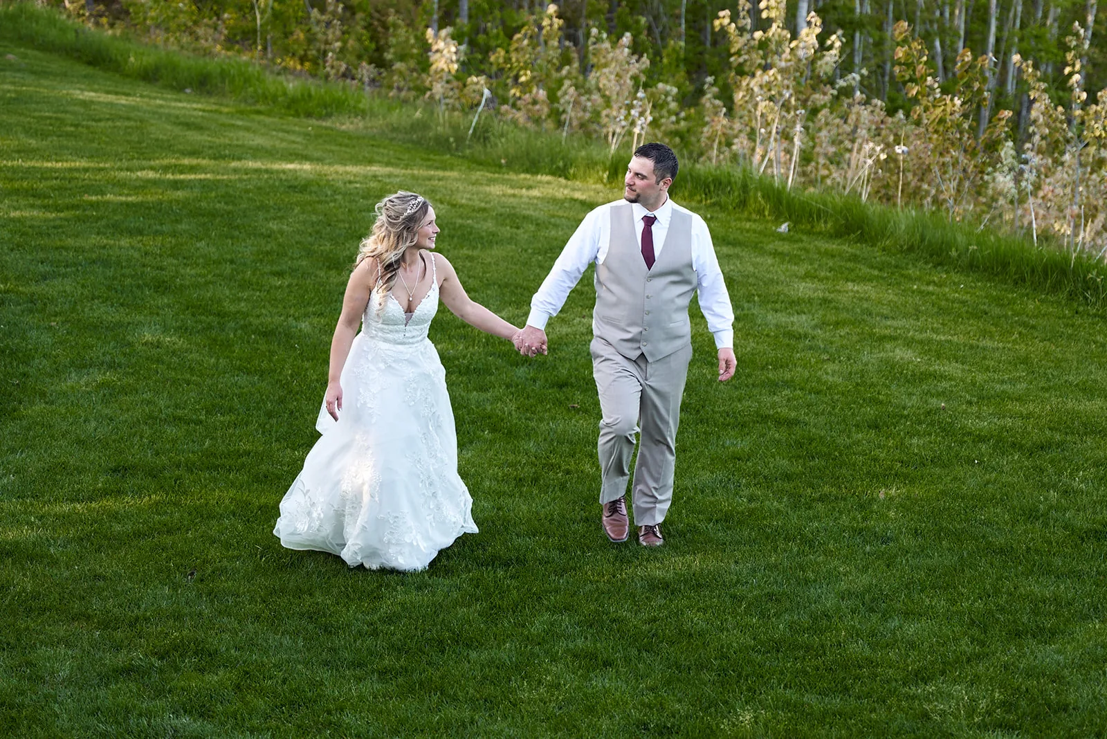 bride and groom walking hand in hand across lawn