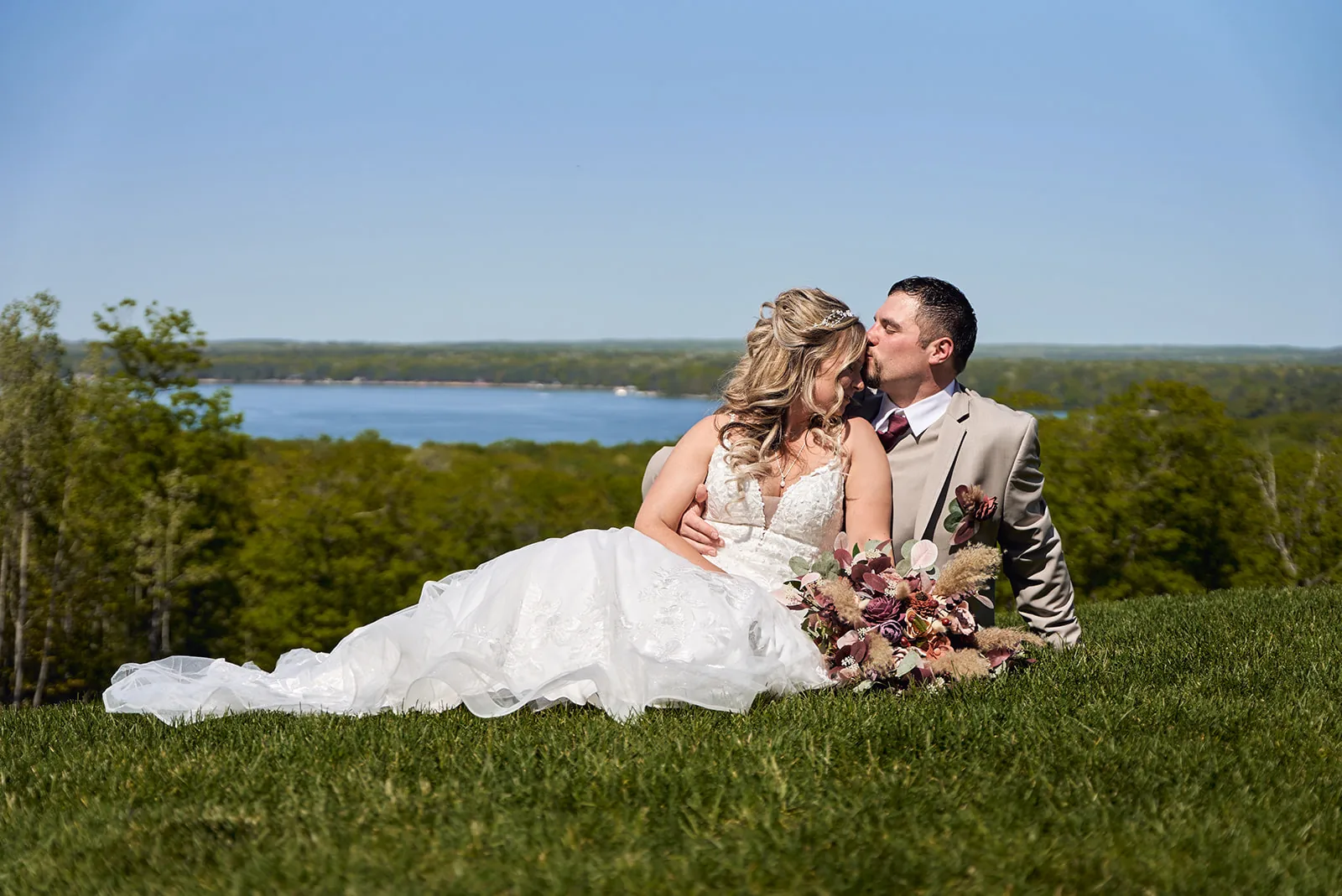 bride and groom lying in grass, lake view, intimate pose