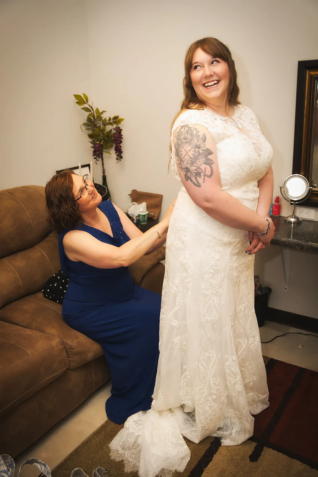 bride getting dress zipped up by helper, getting ready