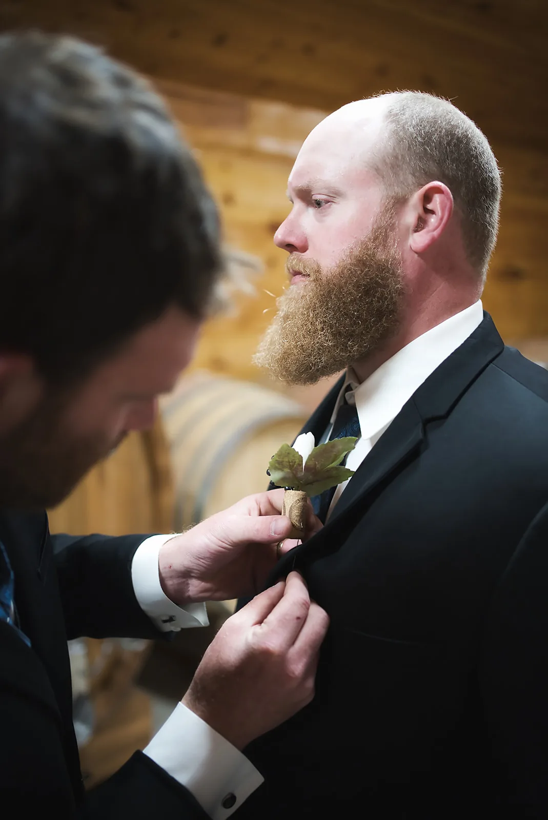 groom solo portrait among wine barrels, adjusting tie